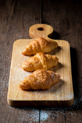 The newly baked croissant is placed on a wooden tray placed on a wooden table.