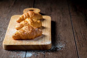The newly baked croissant is placed on a wooden tray placed on a wooden table.