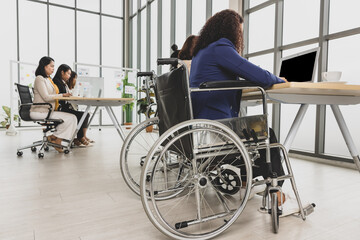 Asian business women including handicap woman sitting on wheelchair working hard on laptop on the table in office. Concept for business meeting