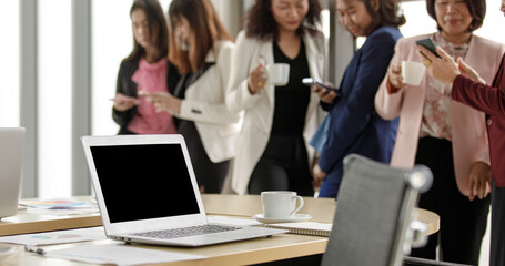 Selective focus on working desk, group of unrecognizable businesswomen standing together in office...