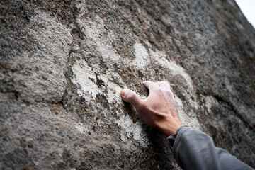 close-up of male hands climbing a stone wall