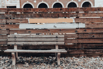 Bench with similar fence & painted board shapes behind it.  Arched building architecture in the background. 