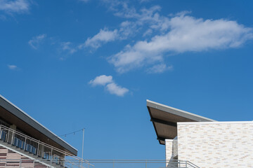 Looking up angle of building tops, cantilever roof angled with sky above. 