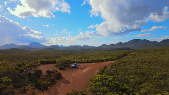 Aerial, car parked in forested landscape with distant mountains, Western Australia