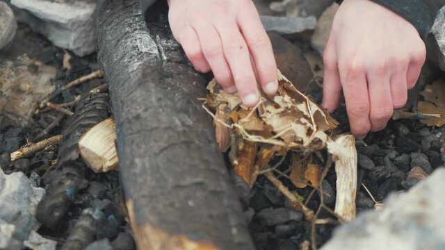 Close up of hands making campfire with dry leaves