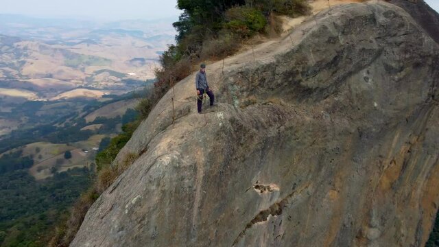 A rock climber stands in victory after the challenging ascent up Pedra Do Bau. A popular location in the Mantiqueria Mountains in Brazil for outdoor adventurers.