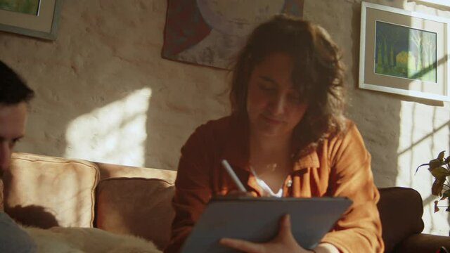 Latin couple have fun drawing on an iPad, close up low angle pan