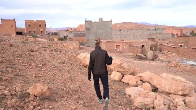 A beautiful caucasian tourist walks among a rural Moroccan village and explores on her own