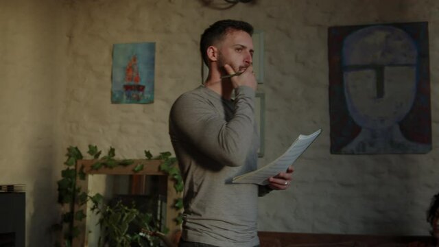 Young composer man think about song  lyrics standing in the living room