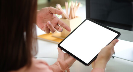 Cropped shot businesswoman holding digital tablet and working with her colleague in office.