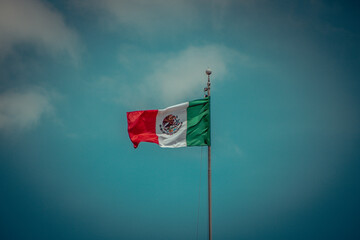 Mexican flag waving in the air under blue sky