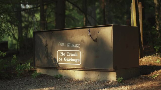 An animal proof food storage safe at a campsite in Glacier National Park. A man stores his food in the box for safety.