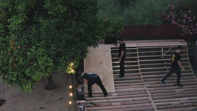 Three Men Building A Skate Ramp In Their Back Yard. Aerial Circling Shot.