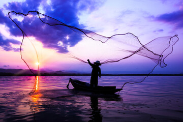Silhouetted of fisherman catching fish in the lake.