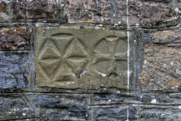 Closeup shot of a solarium sign and cross engraved on stones in the wall