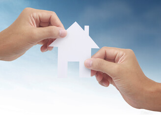 Hands holding paper house, family home  protecting insurance concept