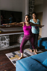 Young latin yoga teacher helping woman with yoga poses in Latin America