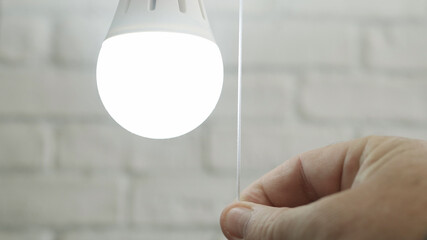Image with a Man Switching ON a LED Bulb in a Room.