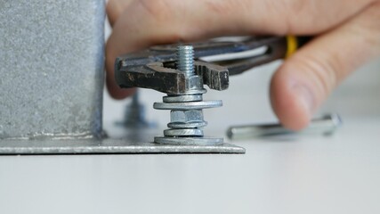 Constructor Screwing a Nut onto a Metal Screw and Tightly Secure a Part of a Mechanical Assembly