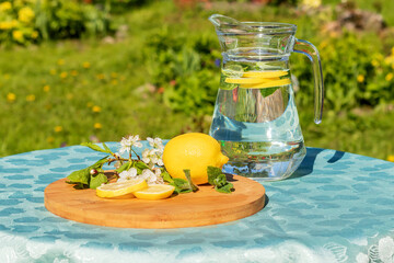 On a garden table in a glass jug, a citrus vitamin drink with mint leaves. 