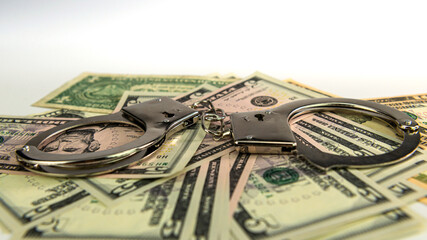 handcuffs on money background, dollar bills, money cash corruption, dirty money, police handcuffs