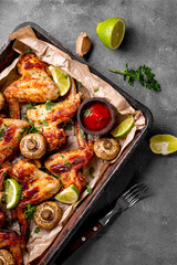 Fototapeta na wymiar Baked homemade chicken wings with mushrooms and lime, vertical photo