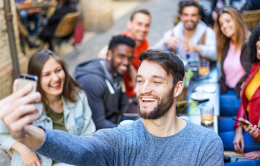 Happy man taking selfie while young people having fun together at coffee bar