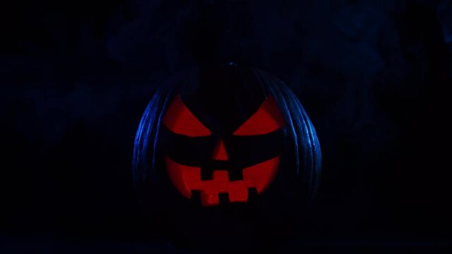 Scary laughing pumpkin on a dark background. Halloween, witchcraft and magic.