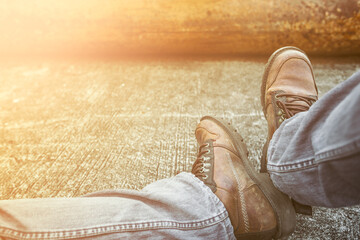 Close-up man's lags in jeans and old boots