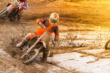 Motocross rider splashing mud on wet and muddy terrain.