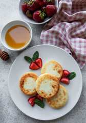Cottage cheese pancakes, ricotta fritters on ceramic plate with  fresh strawberry.