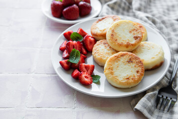 Cottage cheese pancakes, ricotta fritters on ceramic plate with  fresh strawberry.