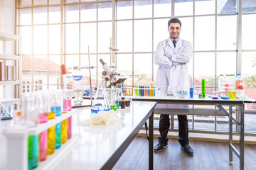 Confident scientist portrait of Happy male scientist keeping arms crossed in a chemistry lab scientist holding test tube with sample in Laboratory analysis background