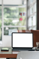Blank white screen tablet with magic keyboard on wooden table in modern living room.