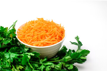 Grated carrot in a white bowl and fresh green parsley isolated on white. Set of vegetables for diet food. Selective focus. Side and top view.