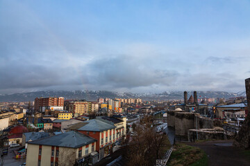 トルコ　エルズルムのエルズルム城から見える街並みとチフテ・ミナーレと雪の積もったパランドケン山と虹のかかった空