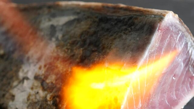 和食のカツオのたたき。表面をガスバーナーで炙るクローズアップ動画。
