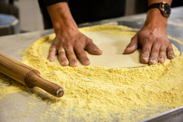 Professional chef cooking in the kitchen restaurant at the hotel, preparing dinner. A cook in an apron makes a pizza. man rolls out pizza dough