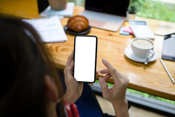 Young woman using smart phone while sitting in coffee shop.