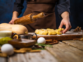 The chef holds a rolling pin in his hand, he prepares the dough for the American pumpkin pie. Lots of ingredients. Wooden texture. Step by step recipe. Cooking, pastry, bakery, home cooking.