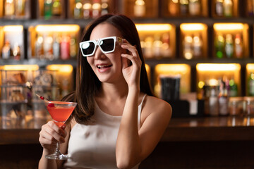 Nightlife concept a sexy girl wearing sunglasses looking mysterious with a straight face holding a...
