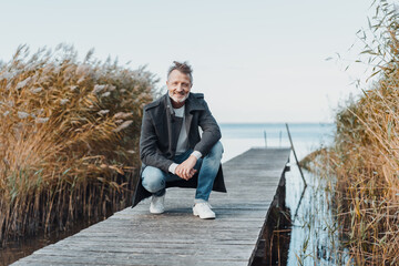 Athletic senior man crouching on an old wooden jetty