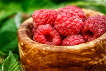 Fresh juicy raspberries in wooden bowl. Summer still life with raspberries on an old wooden table....