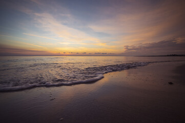 Fototapeta premium Alba sul mare con cielo e qualche nuvola, riflessi della luce sull'acqua.