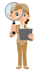 書類を手に持ち虫眼鏡を覗くベージュ色の作業着の女性の全身
