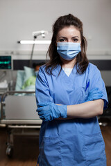 Fototapeta na wymiar Portrait of woman working as nurse at clinic in hospital ward looking at camera with uniform and protection face mask. Caucasian specialist adult with medical occupation for healthcare