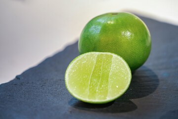 close up fresh lime, lemone in studio light on black stone plate in the kitchen.