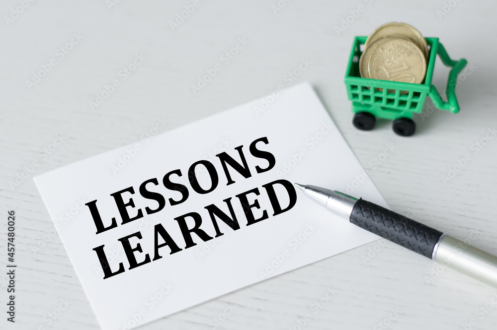 Poster business concept. card with text lessons learned on the table next to a pen and coins in a shopping 