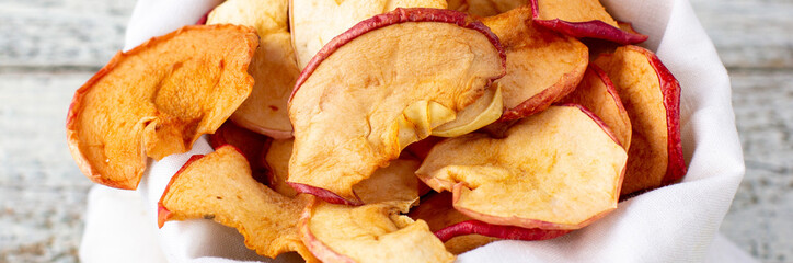 banner of A pile of dried slices of apples in white pouch on wooden background. Dried fruit chips. Healthy food