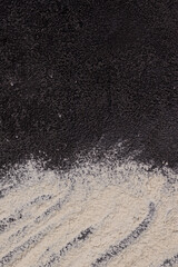 white flour on a black structural background. The beginning of cooking. Process.